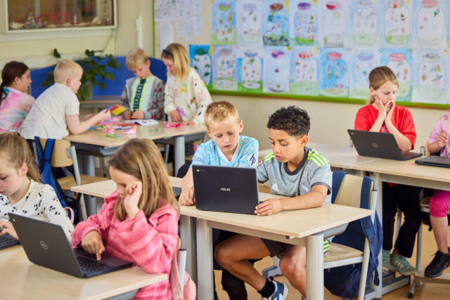 Basisschool kinderen werken aan open leermateriaal.